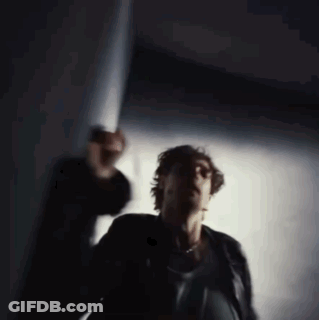 A Blurry Photo Of A Man In A Black Jacket Standing In A Dark Room GIF