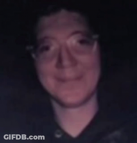 A Blurry Photo Of A Man Wearing Glasses And A Black Shirt GIF