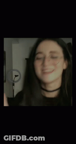 A Blurry Photo Of A Woman Wearing Glasses And A Choker . GIF