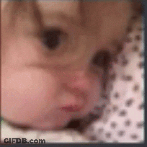 A Blurry Picture Of A Baby 'S Face With A Polka Dot Shirt . GIF