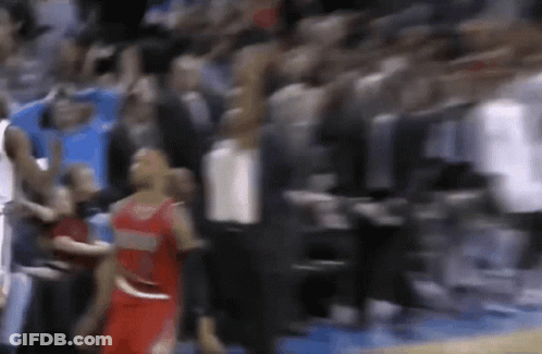 A Blurry Picture Of A Basketball Game With A Player In A Red Jersey Standing In Front Of A Crowd . GIF