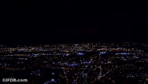 A Blurry Picture Of A City At Night With A Few Buildings Lit Up Including One That Says ' A ' GIF
