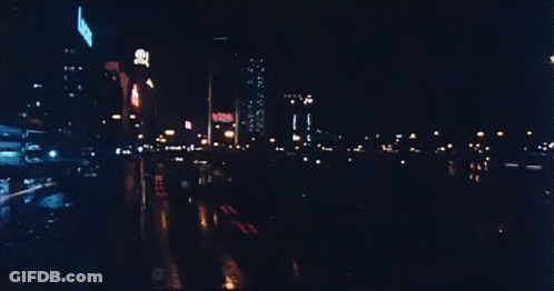 A Blurry Picture Of A City Street At Night With A Sign That Says ' No Smoking ' GIF