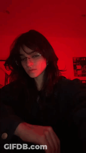 A Blurry Picture Of A Girl Wearing Glasses In Front Of A Red Background GIF