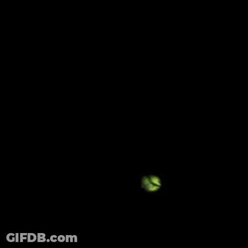 A Blurry Picture Of A Green And Yellow Object On A Dark Background GIF