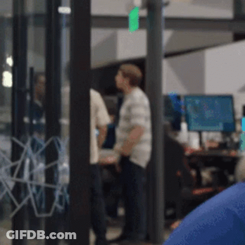 A Blurry Picture Of A Group Of People In A Room With Computers GIF