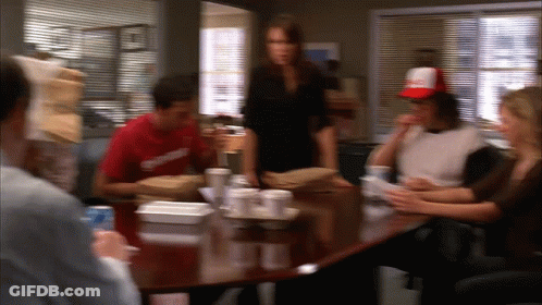 A Blurry Picture Of A Group Of People Sitting Around A Table With A Man Wearing A Red Shirt That Says Supreme GIF