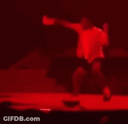 A Blurry Picture Of A Man Dancing On A Stage In A Dark Room . GIF