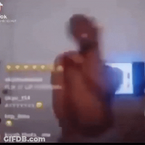 A Blurry Picture Of A Man Holding A Microphone In Front Of A Tv Screen GIF