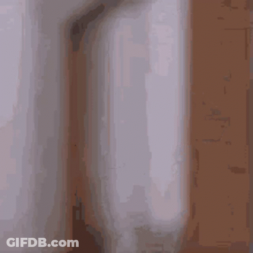 A Blurry Picture Of A Man In A Bathrobe Standing In A Room . GIF