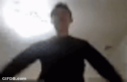 A Blurry Picture Of A Man In A Black Shirt Standing In Front Of A Light . GIF