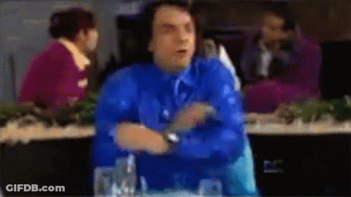 A Blurry Picture Of A Man In A Blue Shirt And Tie Sitting At A Table GIF