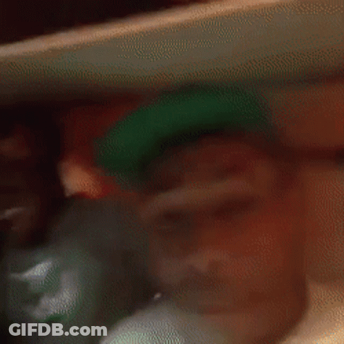 A Blurry Picture Of A Man In A Green Hat . GIF