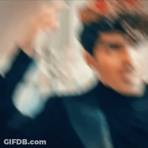 A Blurry Picture Of A Man In A Suit And Tie Holding A Stack Of Money . GIF