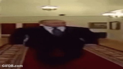 A Blurry Picture Of A Man In A Suit And Tie Walking Down A Red Carpet . GIF