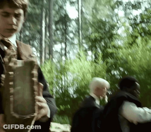 A Blurry Picture Of A Man In A Suit And Tie Walking In A Forest GIF