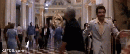 A Blurry Picture Of A Man In A Suit Standing In A Lobby Of A Hotel . GIF