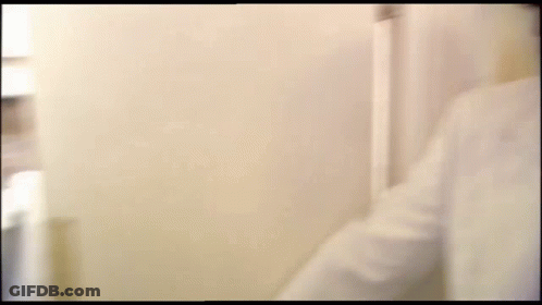 A Blurry Picture Of A Man 'S Face Behind A White Wall . GIF