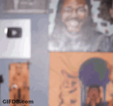 A Blurry Picture Of A Man 'S Face Is Hanging On A Wall Next To A Painting Of A Cat . GIF