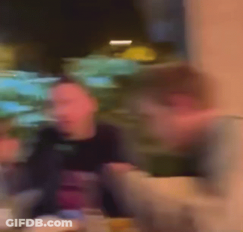 A Blurry Picture Of A Man Sitting At A Table In A Restaurant Eating Food . GIF