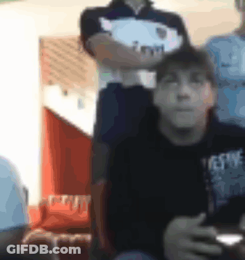 A Blurry Picture Of A Man Sitting In A Chair Holding A Remote Control . GIF