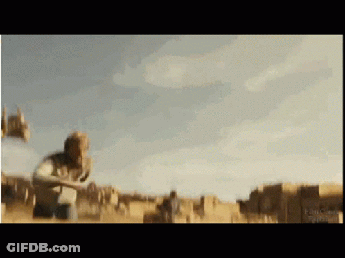 A Blurry Picture Of A Man Standing In A Field With Buildings In The Background . GIF
