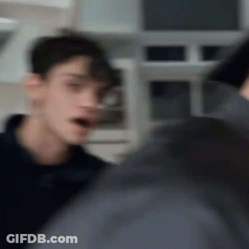 A Blurry Picture Of A Man Standing In A Kitchen Talking To Another Man . GIF