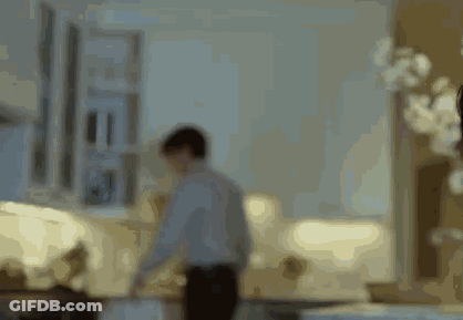 A Blurry Picture Of A Man Standing In A Living Room With A Couch . GIF