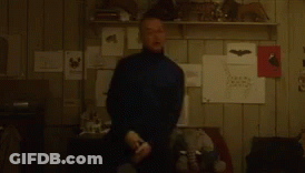 A Blurry Picture Of A Man Standing In A Room With A Shelf Full Of Drawings . GIF