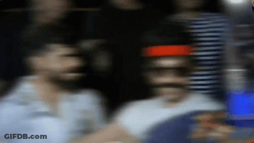 A Blurry Picture Of A Man Standing In Front Of A Red Light GIF
