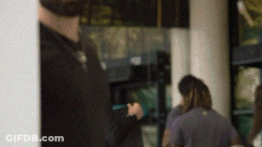 A Blurry Picture Of A Man Standing In Front Of A Window Holding A Cell Phone . GIF