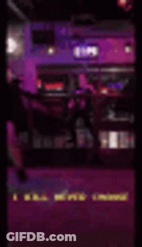 A Blurry Picture Of A Man Standing On A Stage In A Dark Room With Purple Lights . GIF