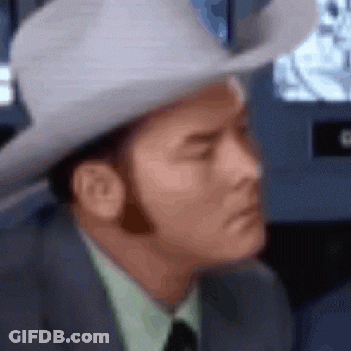A Blurry Picture Of A Man Wearing A Cowboy Hat And A Suit GIF