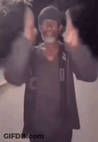 A Blurry Picture Of A Man Wearing A Mask And A Hat Giving The Middle Finger . GIF