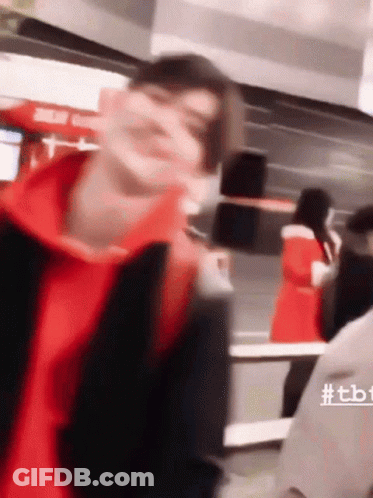 A Blurry Picture Of A Man Wearing A Red Hoodie And A Black Jacket GIF