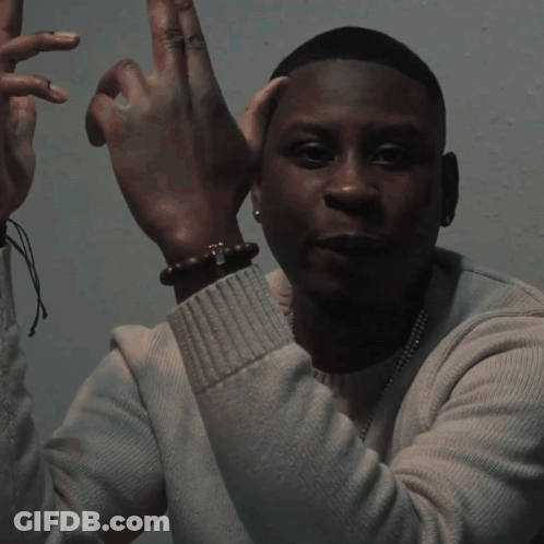 A Blurry Picture Of A Man Wearing A White Shirt And A Necklace GIF
