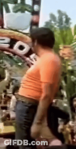 A Blurry Picture Of A Man Wearing An Orange Shirt And A Hat GIF