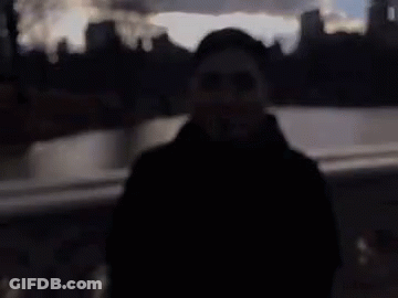 A Blurry Picture Of A Man Wearing Sunglasses And A Black Coat . GIF