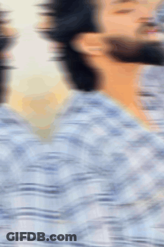 A Blurry Picture Of A Man With A Beard In A Plaid Shirt GIF