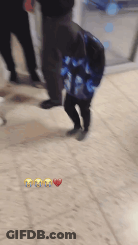 A Blurry Picture Of A Person Carrying A Bag With A Heart And Three Crying Faces On It GIF