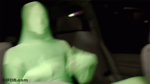 A Blurry Picture Of A Person In A Green Suit Sitting In A Car . GIF