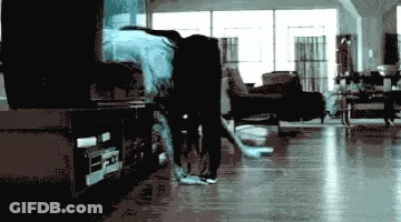 A Blurry Picture Of A Person In A Living Room With A Tv In The Background GIF