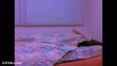 A Blurry Picture Of A Person Laying On A Bed With A Blanket . GIF