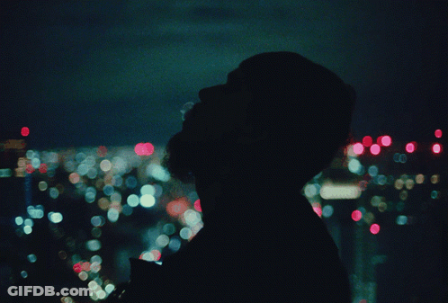 A Blurry Picture Of A Person Looking Out A Window At A City At Night GIF