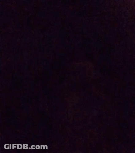 A Blurry Picture Of A Person 'S Face In A Dark Room With A Purple Background . GIF