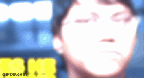A Blurry Picture Of A Person 'S Face With A Yellow Sign In The Background That Says ' Snm ' GIF