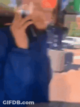 A Blurry Picture Of A Person Sitting At A Table Talking On A Cell Phone GIF