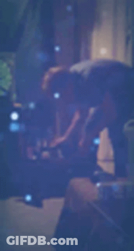 A Blurry Picture Of A Person Standing In A Dark Room With A Blue Background . GIF