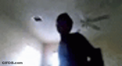 A Blurry Picture Of A Person Standing In A Room With A Ceiling Fan In The Background . GIF