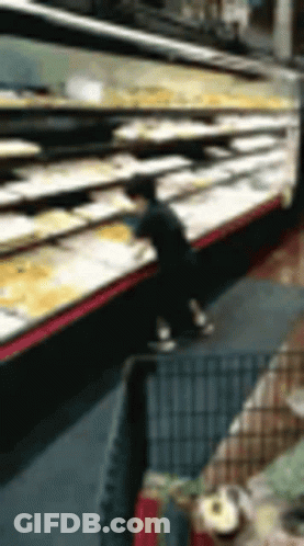 A Blurry Picture Of A Person Standing In Front Of A Display Of Food In A Grocery Store . GIF